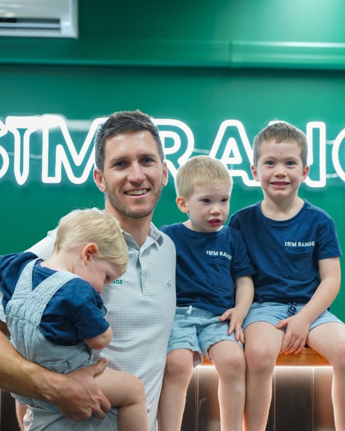 Andy Lancaster and his three boys in front of The Sim Range neon sign
